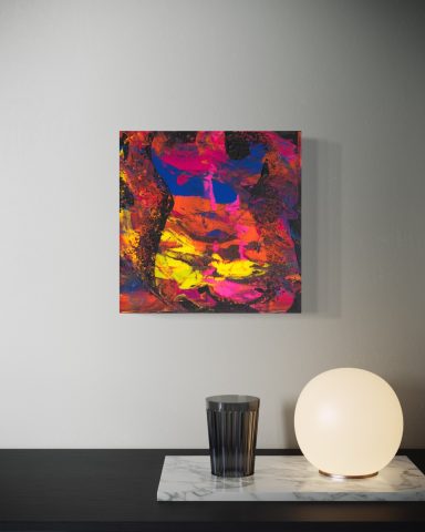 Bunte abstrakte Kunst auf einer Wand, daneben ein Glas und eine runde Lampe.
