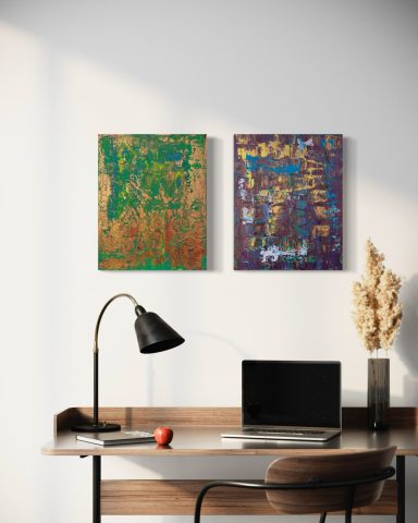 Büroeinrichtung mit zwei bunten Bildern an der Wand und einem Laptop auf dem Tisch.