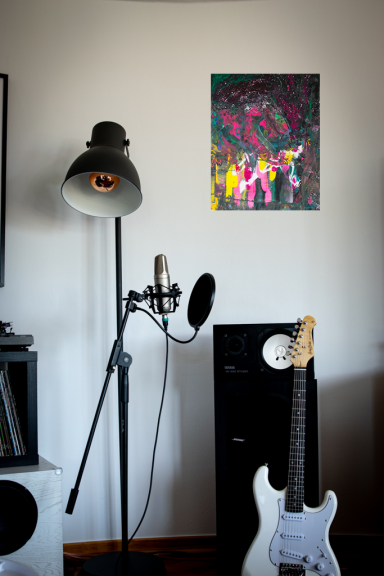 Ein Wohnzimmer mit einer Mikrofonstativ, einer Gitarre, einem Lautsprecher und einem Gemälde.